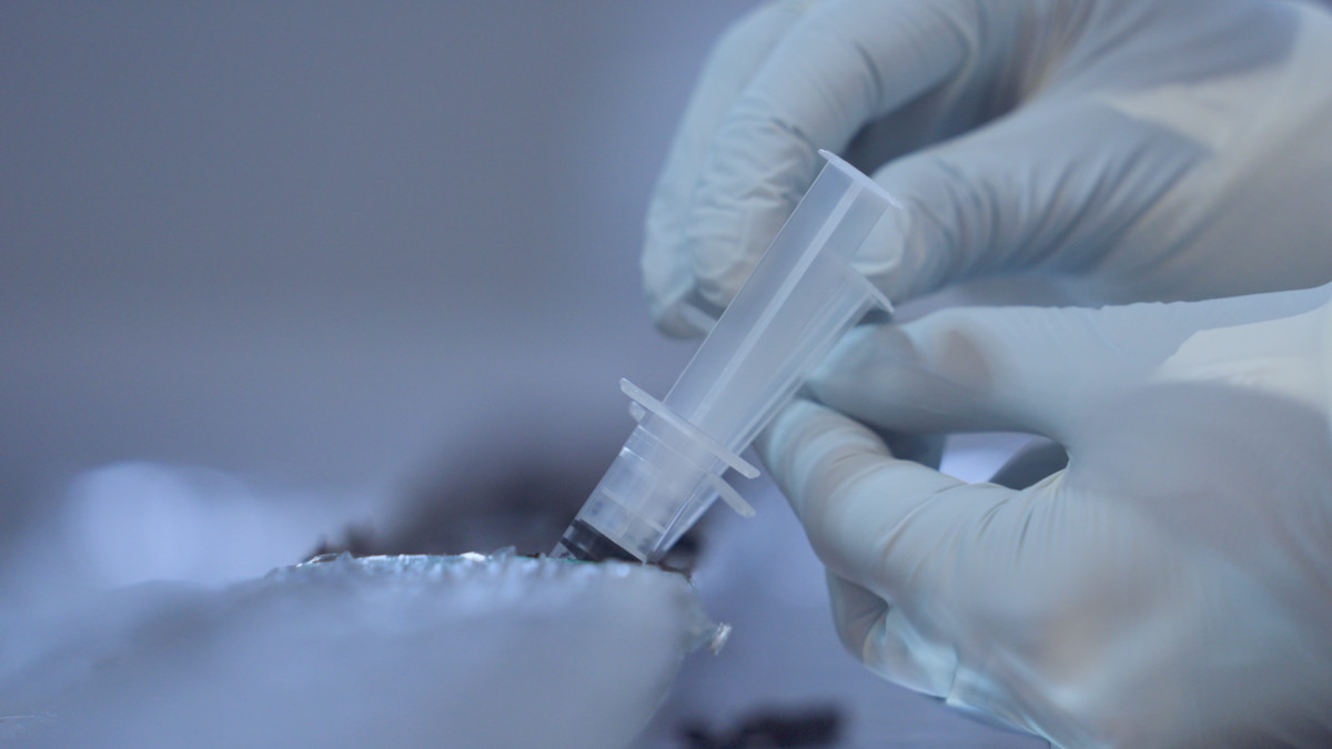 Researcher handling syringe in lab.